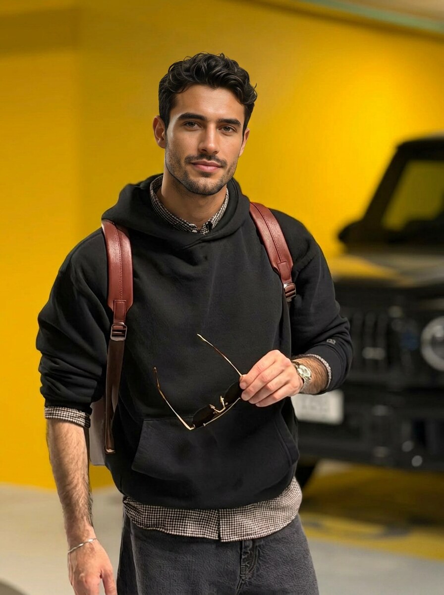 Cyrus wearing the black boyfriend hoodie against a yellow background